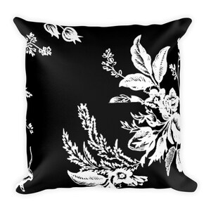 May include: Black and white throw pillow with a floral pattern. The pillow features a repeating design of white flowers and leaves on a black background.