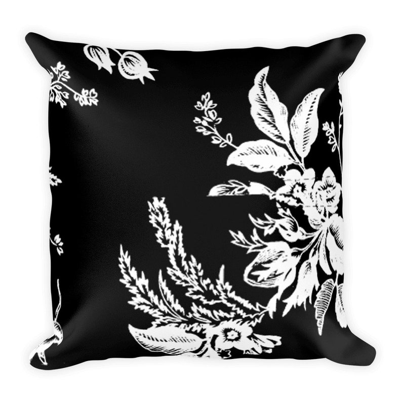 May include: Black and white throw pillow with a floral pattern. The pillow features a repeating design of white flowers and leaves on a black background.