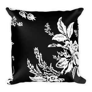 May include: Black and white throw pillow with a floral pattern. The pillow features a repeating design of white flowers and leaves on a black background.