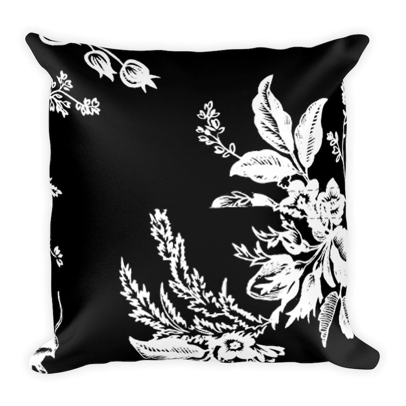 May include: Black and white throw pillow with a floral pattern. The pillow features a repeating design of white flowers and leaves on a black background.