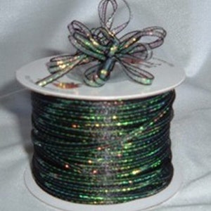 May include: A spool of black iridescent ribbon with a bow on top. The ribbon is wrapped around a white cardboard spool.