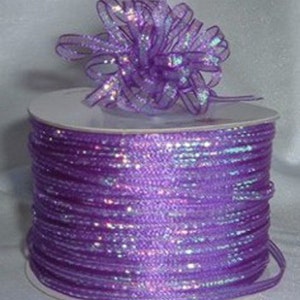 May include: A spool of iridescent purple ribbon with a matching bow on top. The ribbon is shiny and has a subtle sparkle.