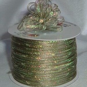 May include: A spool of green iridescent ribbon with a matching bow on top. The ribbon is wrapped around a white cardboard spool.
