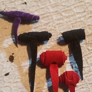 May include: Four leather cord ends in different colors: purple, black, red, and brown. The cord ends are rolled and have a pointed tip.