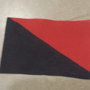 May include: A black and red fabric square with a diagonal line dividing the colors.