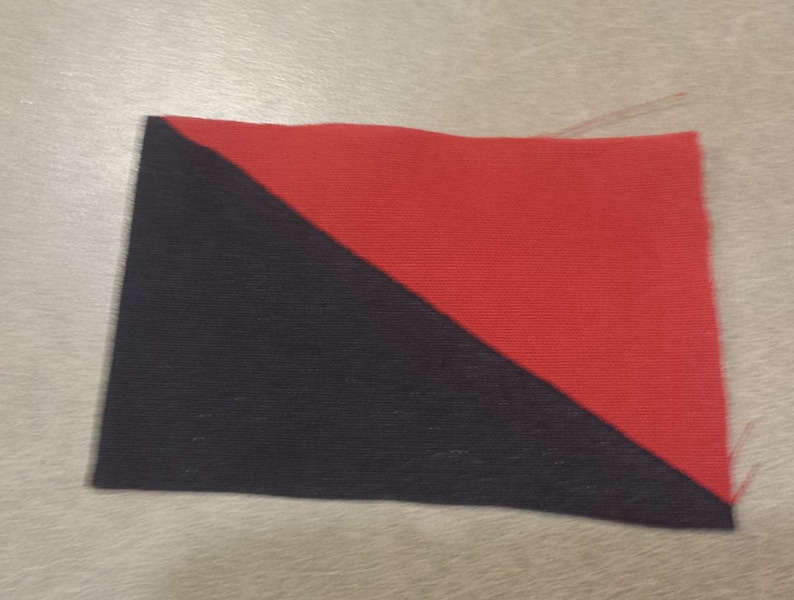 May include: A black and red fabric square with a diagonal line dividing the colors.