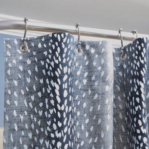 May include: A shower curtain with a blue and white abstract pattern. The curtain has a white background with blue spots of various sizes.