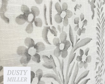 May include: A white fabric with a gray floral pattern. The fabric has a subtle linen texture. The text "DUSTY MILLER" is printed in the lower left corner.