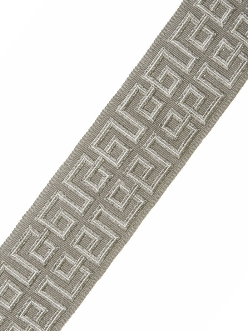 May include: A gray and white woven trim with a geometric pattern. The trim has a subtle sheen and is perfect for adding a touch of elegance to any project.