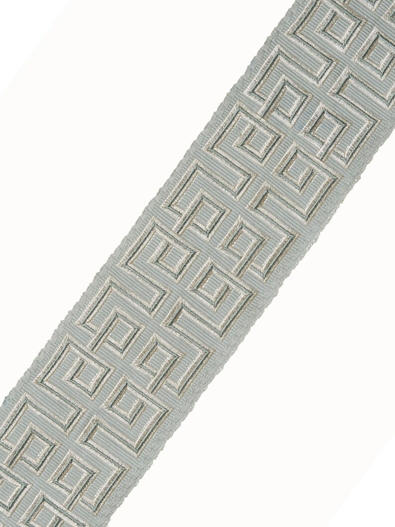 May include: A light blue trim with a silver geometric pattern. The trim has a subtle sheen and a slightly textured surface.