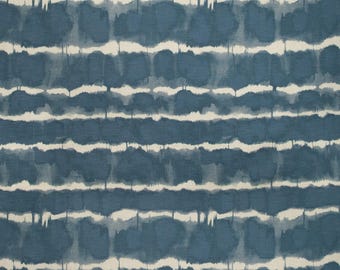 May include: A close-up of a fabric with a blue and white watercolor design. The pattern features horizontal bands of blue with white, irregular lines. The fabric has a textured appearance, suggesting a natural fiber like cotton or linen.