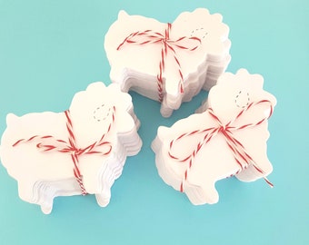 May include: Three stacks of white paper sheep cutouts tied with red and white twine. The sheep have a hole punched in the top for hanging.