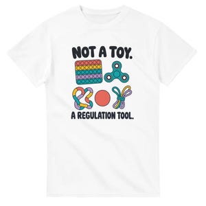 May include: A white short-sleeved t-shirt featuring a graphic print with the text NOT A TOY. A REGULATION TOOL. The design includes illustrations of a multi-coloured square bubble popper, a teal fidget spinner, a tangled loop, a red ball, and a purple cord.