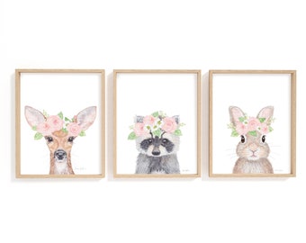 May include: Three framed watercolour paintings of animals wearing flower crowns. The animals are a deer, a raccoon, and a rabbit. The flowers are pink and white.