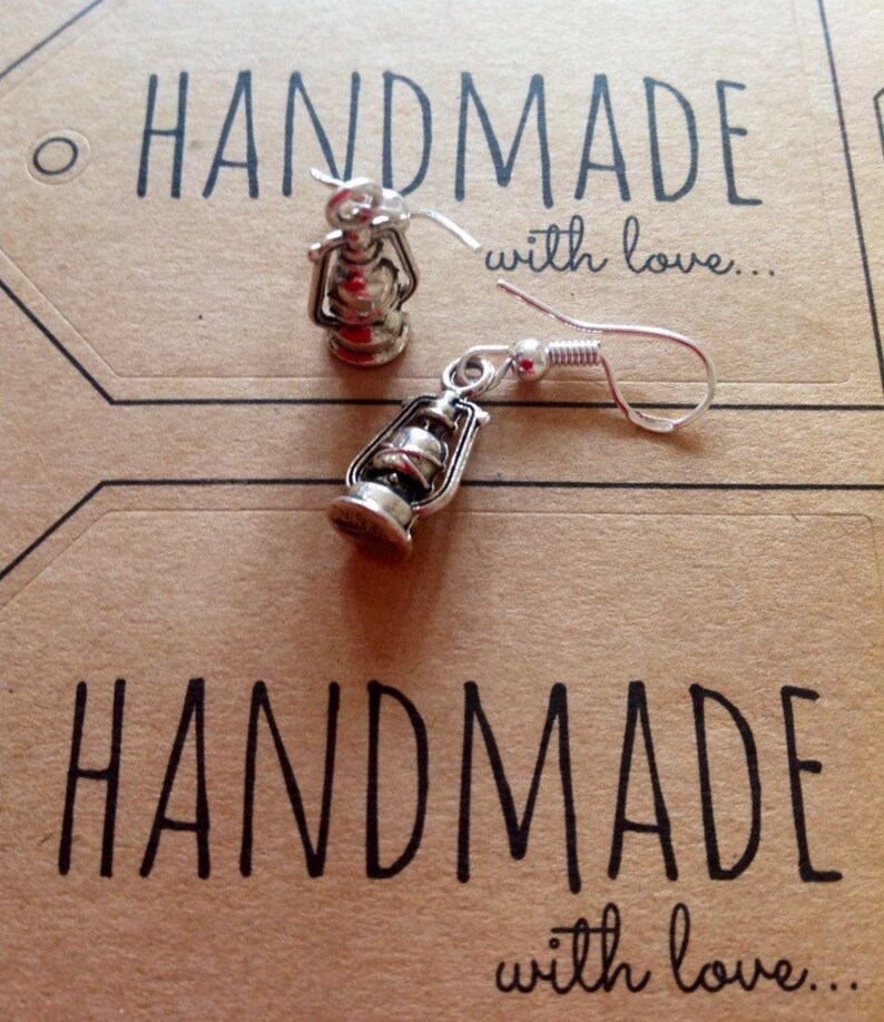 May include: Silver lantern earrings with a hook closure. The earrings are handmade and the card says "Handmade with love..."