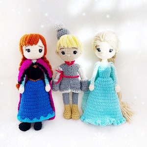 May include: Three crocheted dolls, one with red hair and a blue dress, one with blonde hair and a grey dress, and one with blonde hair and a light blue dress.