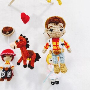 Puede incluir: Un m&oacute;vil de crochet con personajes de la pel&iacute;cula Toy Story. El m&oacute;vil incluye a Woody, Jessie, Bullseye y un coraz&oacute;n. Los personajes est&aacute;n hechos de hilo y tienen detalles bordados.