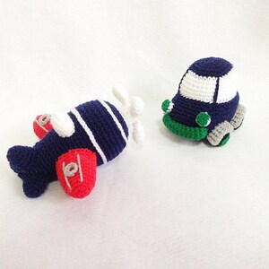 May include: Two handmade crochet toys: a navy blue airplane with red wings and a white propeller, and a navy blue car with a white roof and green and grey accents. The toys are designed for children.