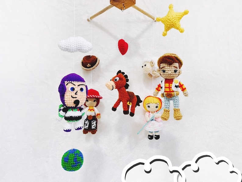 Puede incluir: Un m&oacute;vil de beb&eacute; de crochet con una variedad de personajes de la franquicia Toy Story, incluyendo Woody, Buzz Lightyear, Jessie y Bullseye. El m&oacute;vil tambi&eacute;n incluye una nube, una estrella y un coraz&oacute;n.