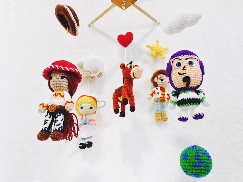 Puede incluir: Un m&oacute;vil de crochet con personajes de la pel&iacute;cula Toy Story. El m&oacute;vil incluye a Woody, Jessie, Buzz Lightyear, Bullseye, una nube, una estrella, un coraz&oacute;n y un globo terr&aacute;queo.