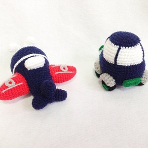 May include: Two handmade crochet toys: a navy blue aeroplane with red wings and a white accent, and a navy blue car with a white top and grey wheels. The aeroplane has white propellers and the car has green accents.