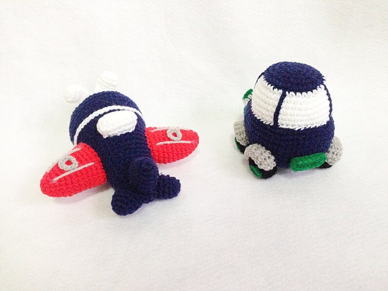 May include: Two handmade crochet toys: a navy blue aeroplane with red wings and a white accent, and a navy blue car with a white top and grey wheels. The aeroplane has white propellers and the car has green accents.