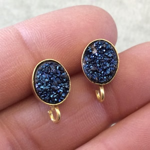 May include: A pair of gold-toned earrings with blue agate stone cabochons. The earrings have a hook closure.