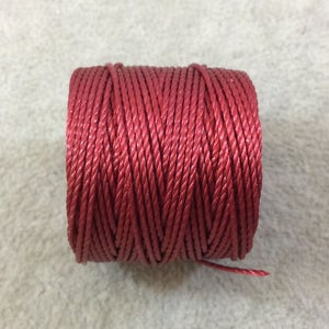 以下が含まれることがあります： 赤いワックスコードの糸巻き。クラフトやジュエリー作りに使用される糸です。