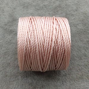 May include: A spool of light pink waxed cord.