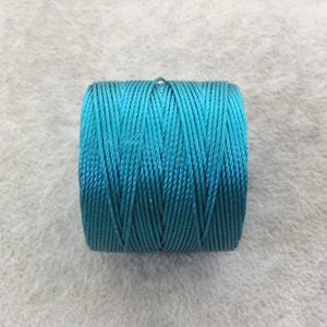 May include: A spool of turquoise-colored cord. The cord is tightly wound, showing a textured surface. The color is a vibrant teal, suitable for various crafting projects. The cord appears to be made of a synthetic material.