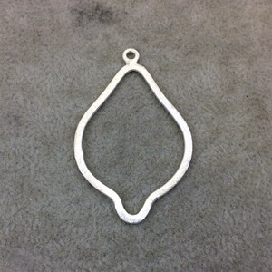 May include: A silver pendant shaped like a lemon, with a loop at the top for attaching a chain.