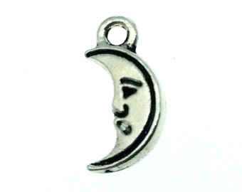 May include: Silver charm in the shape of a crescent moon with a face on it.
