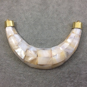 May include: A white crescent-shaped necklace made of mother of pearl tiles with gold metal clasps.
