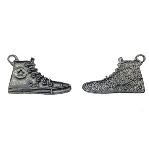 May include: Two silver-toned metal shoe charms in the shape of high-top sneakers. One shoe has a star on the side, the other is plain.