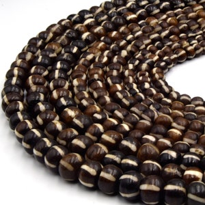 May include: A strand of brown and white striped beads. The beads are round and have a natural, organic look.