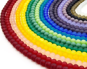 Puede incluir: Una colección de cuentas redondas con acabado mate dispuestas en un patrón de degradado de arcoíris semicircular. Las hebras presentan un espectro de colores que incluye rojo, naranja, amarillo, verde, azul, morado y blanco, con textura.