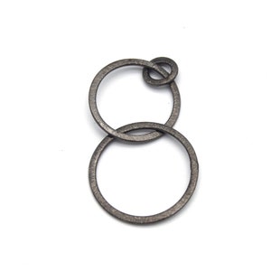 May include: A silver metal ring with two interlocking circles. The circles are connected by a small knot.