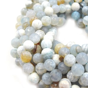 May include: A strand of light blue, white, and yellow agate beads. The beads are faceted and have a natural, organic look.