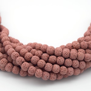 May include: A strand of brown lava rock beads. The beads are round and have a rough, porous texture.