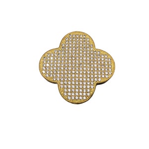 Puede incluir: Un colgante de tr&eacute;bol de oro con un engaste pav&eacute; de piedras redondas transparentes.