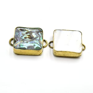 May include: Two square-shaped brass connector pieces with a loop on each side. One piece has a white shell inlay, and the other has a multi-colored abalone shell inlay.