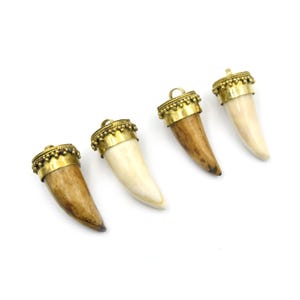May include: Four horn-shaped pendants featuring smooth, tapered off-white and brown organic material tips capped with decorative gold-toned metal settings. Each cap is adorned with a beaded border and a small circular loop for attachment.