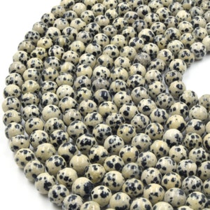 May include: A strand of round, white and black speckled Dalmatian Jasper beads. The beads are approximately 8mm in diameter and have a smooth, polished finish.