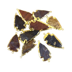 May include: A group of ten arrowhead-shaped agate pendants with gold-plated edges. The pendants are various shades of brown, red, and black. Each pendant has two gold jump rings for attaching to jewelry.