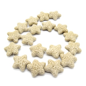 May include: A strand of beige starfish-shaped beads with small, dark brown speckles. The beads are strung together on a thin, clear string, perfect for jewelry making or craft projects. The starfish beads are arranged in a circular pattern against a white background.
