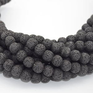 May include: A strand of black lava rock beads. The beads are round and have a rough, porous texture.