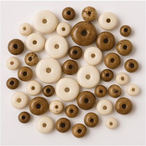 May include: A collection of round, flat, donut-shaped beads in varying sizes. The beads are arranged in a circular cluster and feature a smooth, polished finish in alternating shades of solid cream, light brown, and mottled dark brown tones.