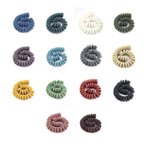 Peut inclure: Une collection de quatorze élastiques à cheveux en spirale disposés en grille, chacun présentant une couleur unie distincte, notamment bleu, vert, blanc, olive, violet, bleu clair, gris, beige, jaune, menthe, rouge, noir, vieux rose et brun.