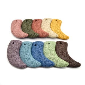 May include: Ten lava rock pendants in various colors, including purple, blue, green, brown, yellow, and beige. Each pendant is shaped like a crescent moon and has a hole for stringing.