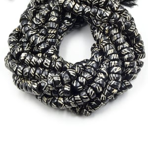 May include: A strand of black and white patterned beads. The beads are made of bone and have a spiral design.